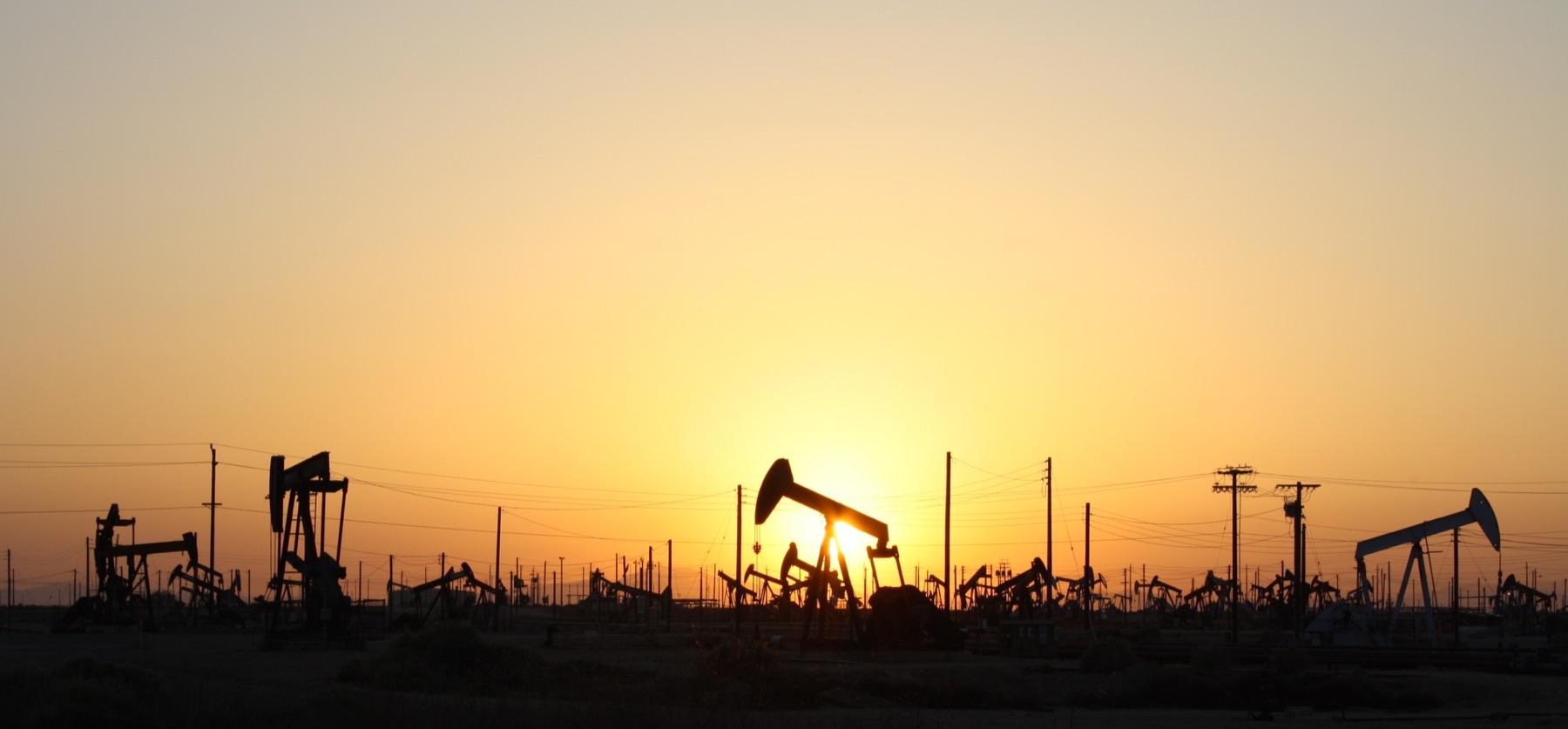 Oil pumpjacks silhouetted against a sunset at the Lost Hills Oil Field in California